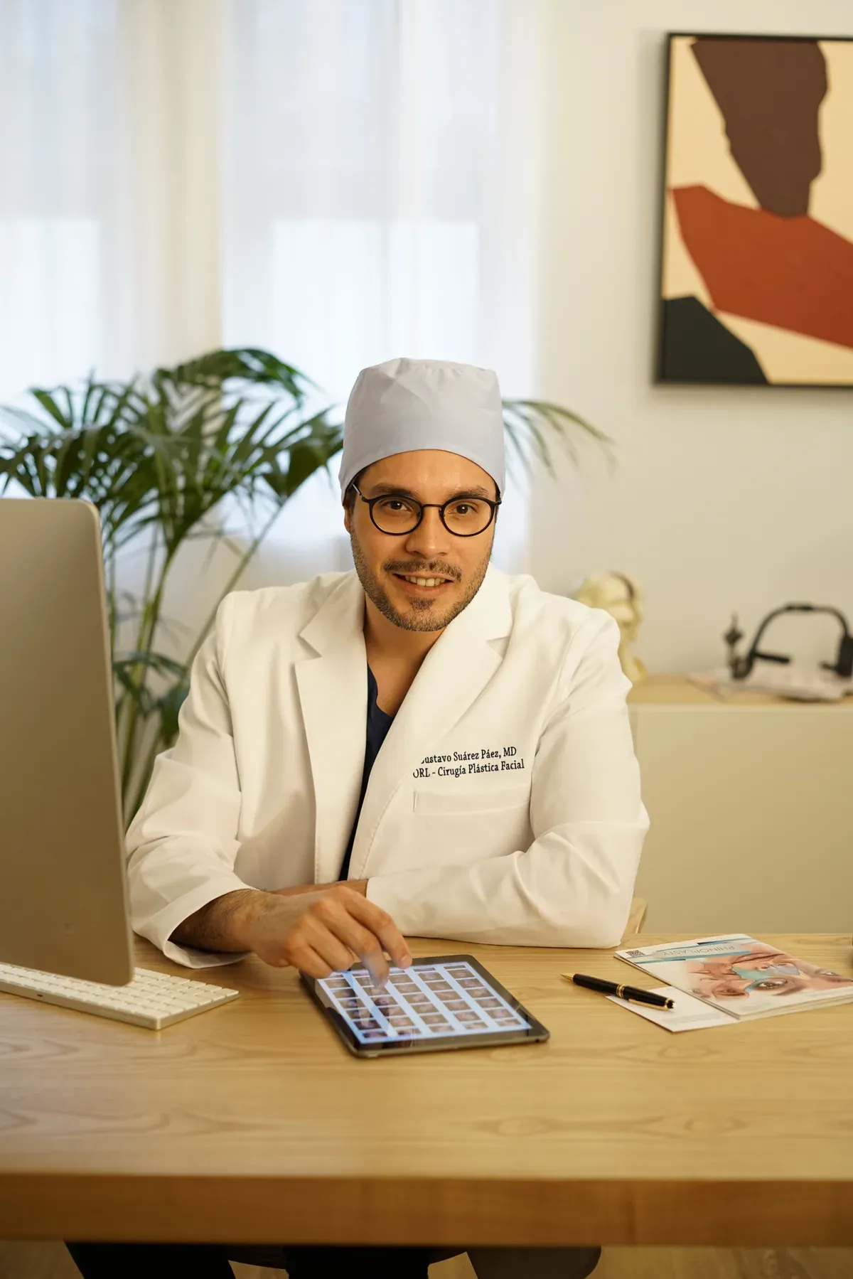 El Dr. Gustavo Suárez sentado en su despacho, con una tableta sobre la mesa