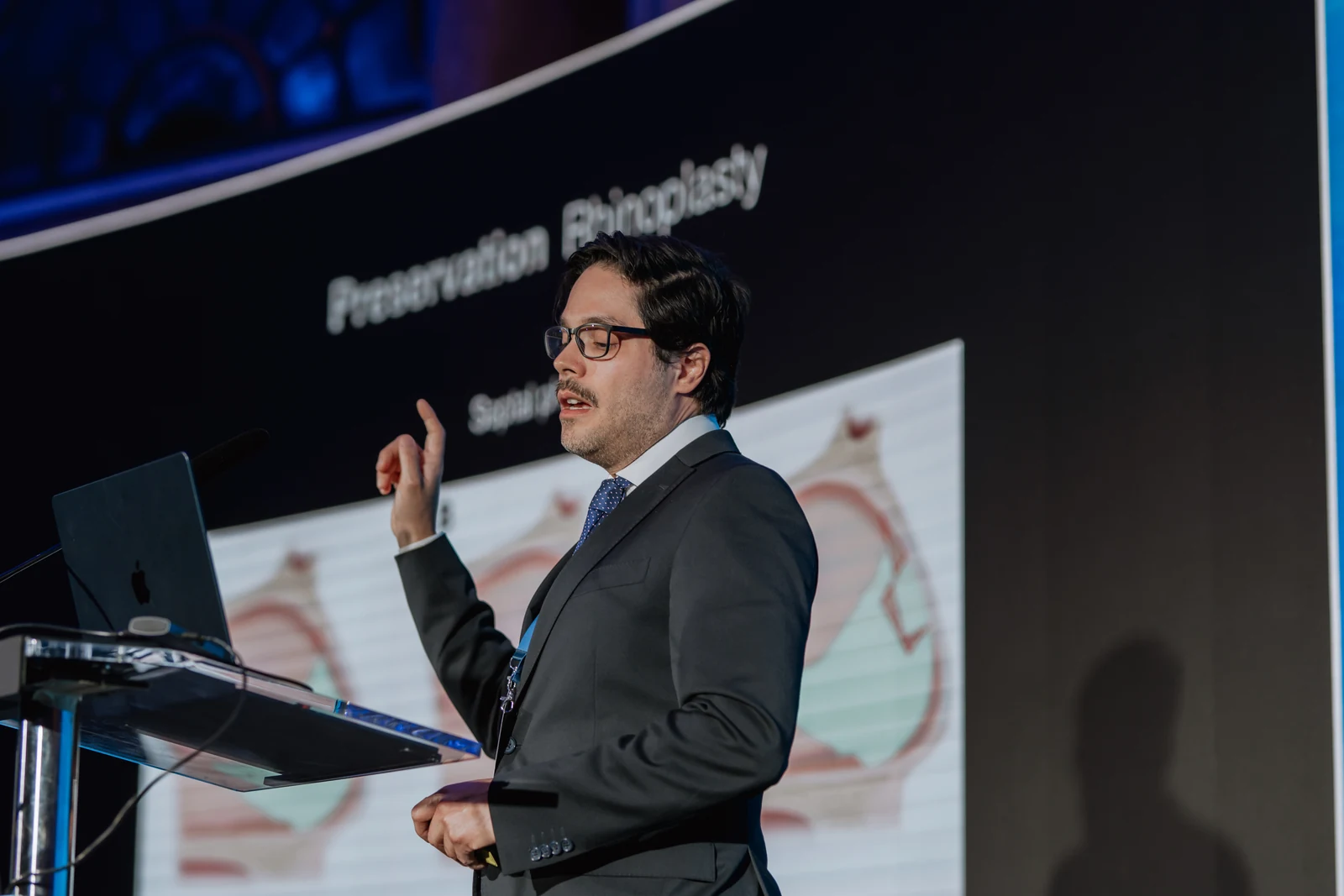 Dr. Gustavo Suárez explaining a technique during a conference, one hand raised